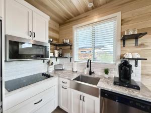 a kitchen with white cabinets and a sink and a window at Escalante Escapes Prickly Pear- Bunk Escape in Escalante