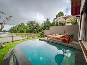 a swimming pool with a bench and an umbrella at Ascarya Ubud in Ubud