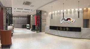 a hotel lobby with a reception desk and chairs at Borrman Hotel Puning International Commodity City Wantaihui in Jieyang