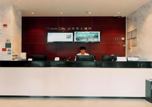 a woman sitting at a desk with a laptop at City Comfort Inn Zhuhai Jinwan Hangkong Xincheng in Zhuhai