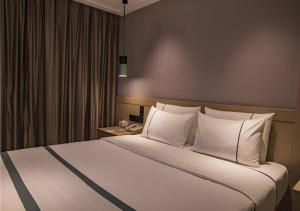 a bedroom with a large bed with white pillows at City Comfort Inn Hainan Tunchang Changsheng Road  +156 photos