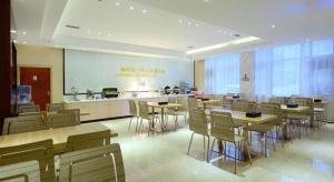 a restaurant with tables and chairs and a kitchen at City Comfort Inn Tongren High-speed Railway Station in Tongren
