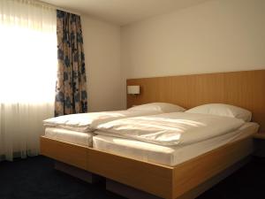 a large bed in a bedroom with a window at Hotel Bahnhof Jestetten in Jestetten