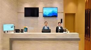 昆明市にあるCity Comfort Inn Kunming High Speed Railway South Station Yongxin Harvardのカウンターに座る2人