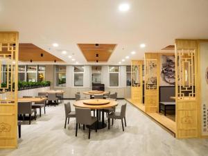 a restaurant with tables and chairs in a room at Shell Hotel Tai'an Feicheng Longshan Road in Muzhuang