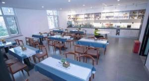 a restaurant with blue tables and chairs and a person at GreenTree Inn Tangshan Nanhu International Exhibition Center in Tangshan