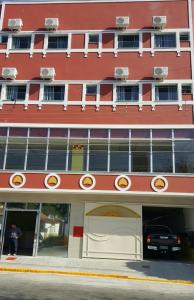 an exterior view of a red building with a parking garage at Hotel Pousada do Papa in Aparecida