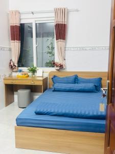 a bedroom with a bed with blue pillows and a desk at SEA HOME HOMESTAY in Ấp Bình Hưng