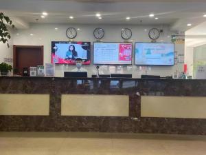 a lobby with a counter with clocks on the wall at GreenTree Inn Dalian Jinzhou District Railway Station Ansheng Plaza in Dalian