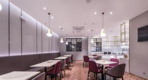 a restaurant with tables and chairs and a kitchen at Borrman Hotel Hezhou High Speed Railway Station Guangming Avenue in Hezhou