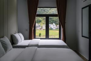 two beds in a room with a window at White House Hotel in Dồng Văn