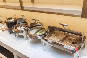 a kitchen counter with three pans of food and a sink at Borrman Hotel Yongzhou High Speed Railway Station in Guzhuting