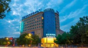 a hotel with a blue building in front of it at City Comfort Inn Jiyuan Jishui Avenue Jigang in Jiyuan