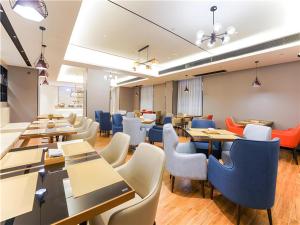 a dining room with tables and chairs at Echarm Hotel Suzhou Shengze Oriental Extile City in Suzhou
