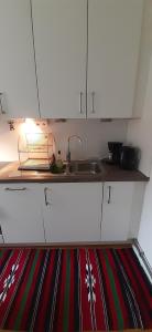 a kitchen with white cabinets and a sink on a rug at Wonderful Stay Helsingborg in Helsingborg +2 photos