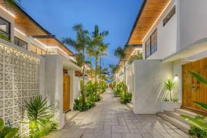 Anjuna Surf & Sunset 2BR Villas in Uluwatu في أُلُواتو: ممشى بين بيتين فيه نخل