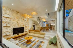 Anjuna Surf & Sunset 2BR Villas in Uluwatu في أُلُواتو: غرفة معيشة مع مدفأة وتلفزيون