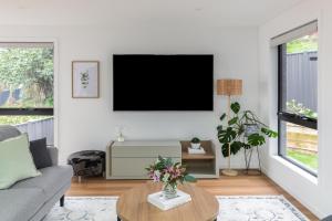 a living room with a flat screen tv on a wall at The Crescent, a modern townhouse near LGH & parks in Kings Park