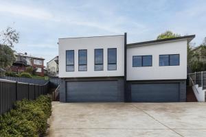 a white house with a garage at The Crescent, a modern townhouse near LGH & parks in Kings Park
