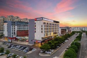 un grand bâtiment avec des voitures garées dans un parking dans l'établissement Borrman Hotel Chongzuo Guangxi Normal University for Nationalities, à Buli