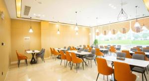 une salle à manger avec tables et chaises et une grande fenêtre dans l'établissement City Comfort Inn Yidu Three Gorges Qianguqing Wanda Plaza, à Yichang