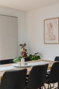 a dining room table with black chairs and a plant at The Crescent, a modern townhouse near LGH & parks in Kings Park
