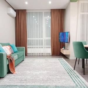 un soggiorno con un divano verde e una televisione di Red and Green a Astana