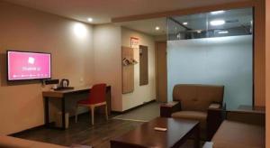 a room with a tv and a couch and a table at Thank Hotel Shandong Weifang North High-speed Railway Station in Weifang