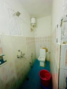 a bathroom with a toilet and a red bucket at Mirvana Guest House & Camel safari in Jaisalmer