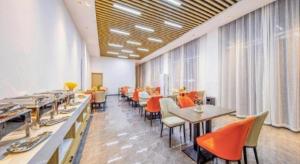 une salle à manger avec tables, chaises et fenêtres dans l'établissement GreenTree Inn Express Dongying Lijin County Ginza Market, à Dongying