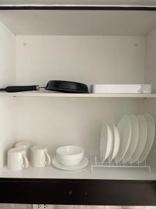 a white shelf with plates and cups and bowls at Kasara Staycation Pasig in Manila
