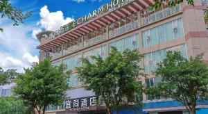 a building with trees in front of it at Echarm Hotel Zigong Machishui Wanda Plaza in Zigong