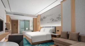 ein Schlafzimmer mit einem weißen Bett und ein Wohnzimmer in der Unterkunft Ramada Encore by Wyndham Jinan Shanghe in Shang-ho-hsien