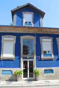 un bâtiment bleu avec deux fenêtres et une porte dans l'établissement Hotel Senhor de Matosinhos, à Matosinhos