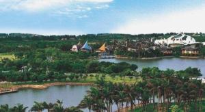 ShenzhenにあるCampanile Hotel Shenzhen Bay Convention and Exhibition Centerのヤシの木と湖のあるリゾートの空中ビュー