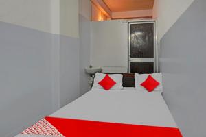 a small room with a bed with red pillows at Super Hotel O Home Town in Patna +26 photos