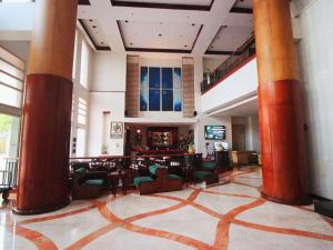 a lobby with red columns and chairs and a bar at Grand Surya Hotel Kediri in Kediri
