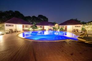 a large blue swimming pool in front of a house at Baan Suan Nuan Ta in Samut Songkhram