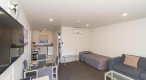 a small living room with a couch and a bed at Hawera Central Motor Lodge in Hawera