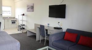 a living room with a couch and a desk with a tv at Hawera Central Motor Lodge in Hawera