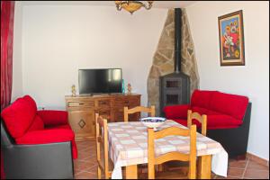 sala de estar con mesa y 2 sillas rojas en Chalet Vigía 114, en Conil de la Frontera