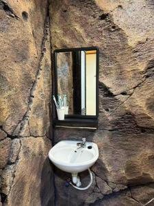 a sink in a stone wall with a mirror at MR B hotel in Bukit Mertajam