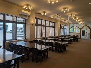 a row of tables and chairs in a room with windows at VillaCheerio in Yamanouchi