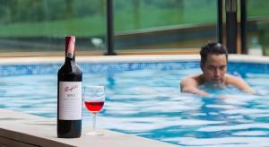 a bottle of wine sitting on a table next to a swimming pool at Chantara Valley Resort in Mu Si