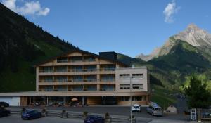 un hôtel avec des voitures garées devant une montagne dans l'établissement Hotel Walserstube, à Warth am Arlberg