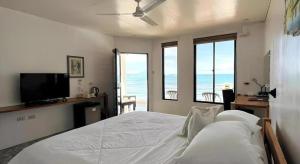 a bedroom with a white bed with a view of the ocean at Coral Beach Club in Matabungkay