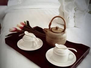 a tray with two cups and a tea pot on a bed at Med Room Korat in Nakhon Ratchasima