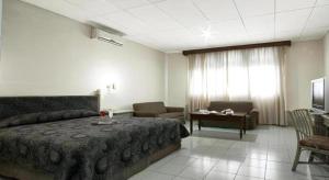 a bedroom with a bed and a couch and a television at Hotel Griyadi Kusuma Sahid in Solo