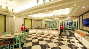 a restaurant with a checkered floor and two people in red shirts at GreenTree Inn Guangyuan Lizhou West Road Business Hotel in Guangyuan