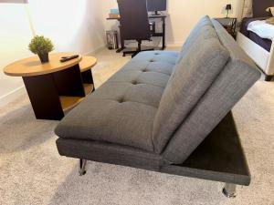 a gray chair in a living room with a table at Cozy and Spacious Suite - Private Ensuit Bath - King Bed - Ultra Fast Wifi - Free Parking - Smart TV in Rockland
